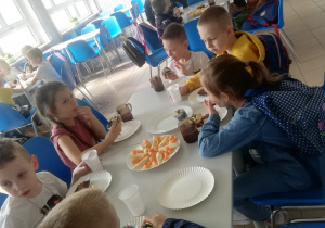 dzieci jedzą babeczki i piją herbatkę na stołówce